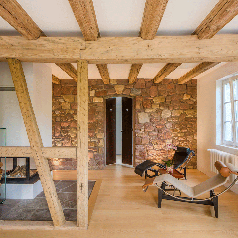 Berstett maison à colombage rénovation alsace architecte surprise adrien puzzuoli architecte parquet mur en ppierre sol en grès charpente apparente chaise le corbusier espace lecture